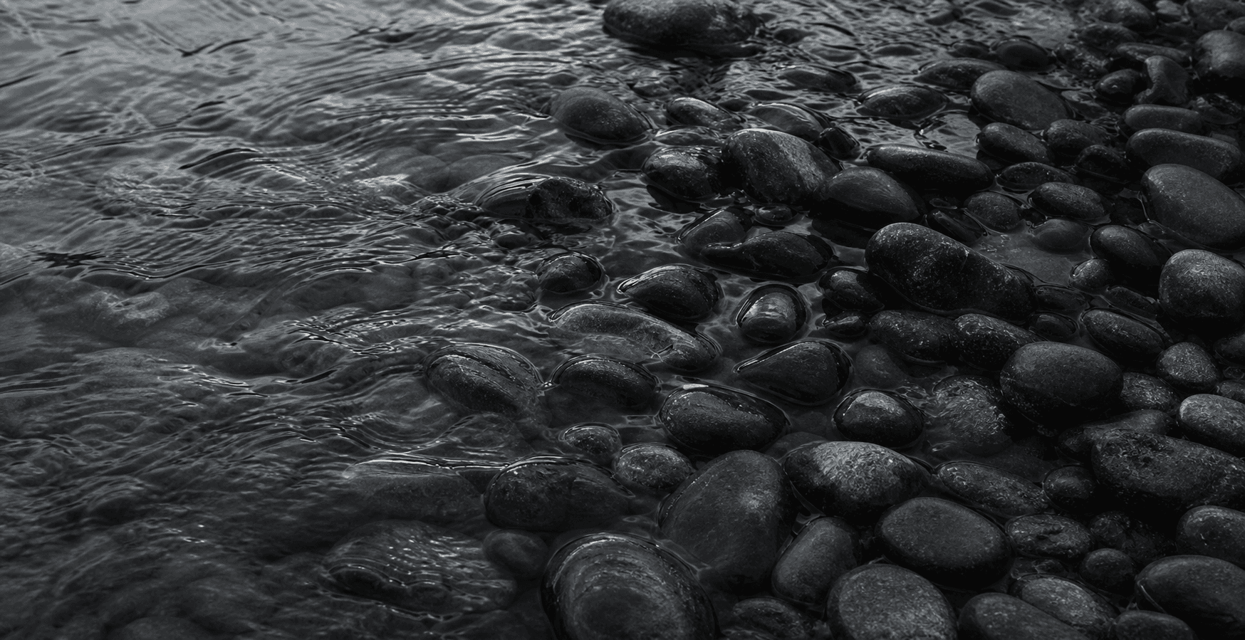 Dark river stones under a thin sheet of moving water